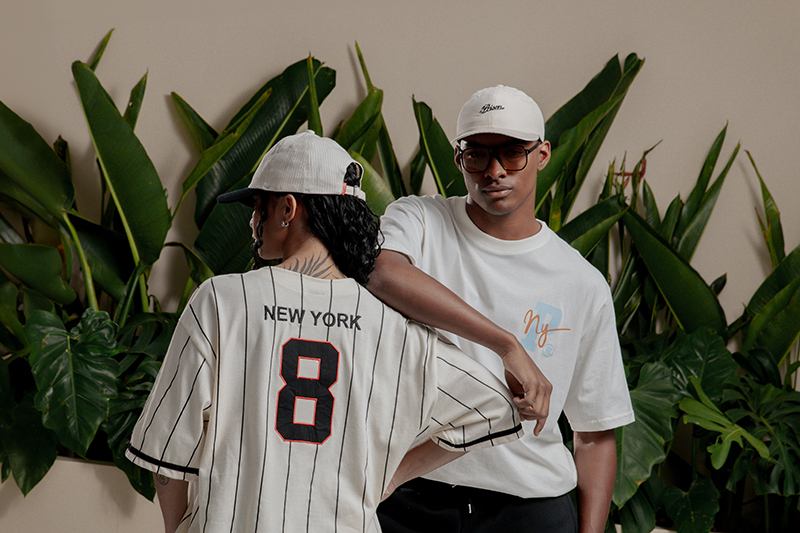 casal com roupa streetwear, boné e camisa de baseball